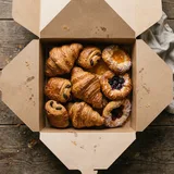 An open kraft box of croissants, pain au chocolat and danishes